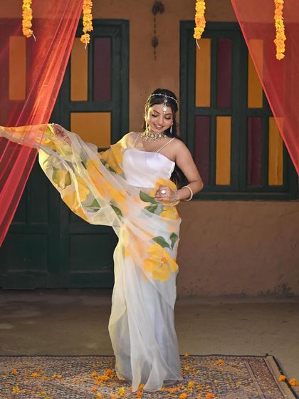 A unique Haldi look with just a hint of yellow. This hand-painted organza saree is a modern and elegant choice, styled with a simple choker and mathapatti for a sophisticated feel.