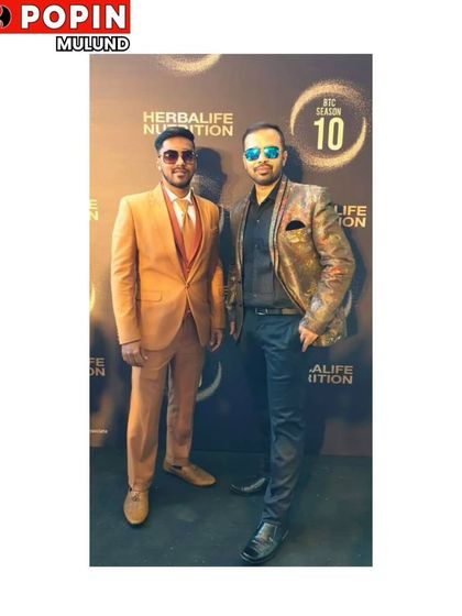 Two clients showing off their style. The man on the left wears a classic tan suit, while the man on the right sports a unique patterned designer blazer.