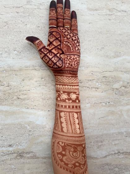 A single-arm view of a bridal design, featuring fish motifs, paisleys, and dense check patterns.