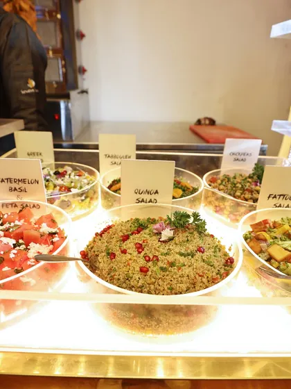 A fresh salad bar featuring a variety of healthy options like Watermelon Basil Feta Salad and Quinoa Salad, catering to all dietary preferences.