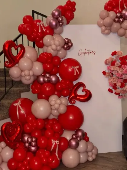 A romantic Valentine's Day balloon arrangement designed to cascade down a staircase, using shades of red and pink with heart-shaped foil balloons.