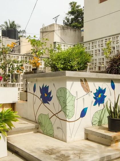 A functional water tank on a terrace is transformed into a piece of art with a floral mural. This small intervention adds a layer of flamboyance and personality, turning a utilitarian object into a garden feature.
