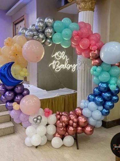 An "Oh Baby" ring decoration with a celestial touch. This colorful balloon arch includes a moon prop and a neon sign, creating a unique and eye-catching backdrop.