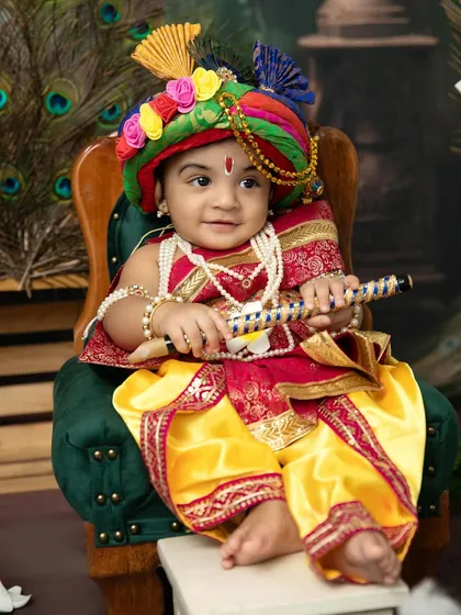 A regal portrait of a little Krishna in a colorful turban. The detailed costume and traditional props make these festival photos truly stand out.