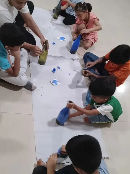 Kids work together on a bottle painting project, learning about recycling and creative expression as they turn simple bottles into colorful art pieces.