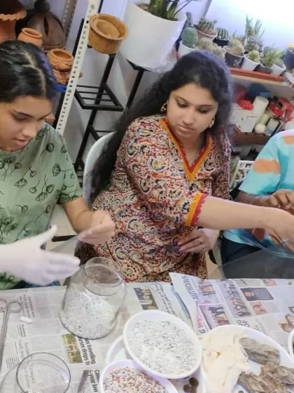 Two participants fully engaged in the terrarium making process at our studio. We provide all the materials, including various soils, pebbles, and tools, so you can focus on the creative experience.