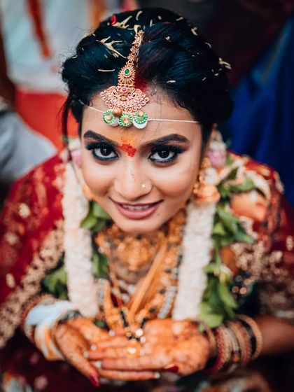 A beautiful close-up portrait of a South Indian bride looking directly at the camera, her eyes full of happiness.
