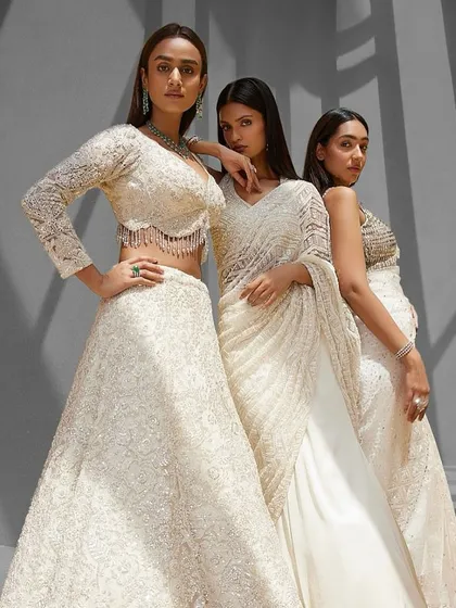 Three models showcase the versatility of Istya's ivory collection, featuring a lehenga, a saree, and a sharara set, all united by their exquisite craftsmanship.
