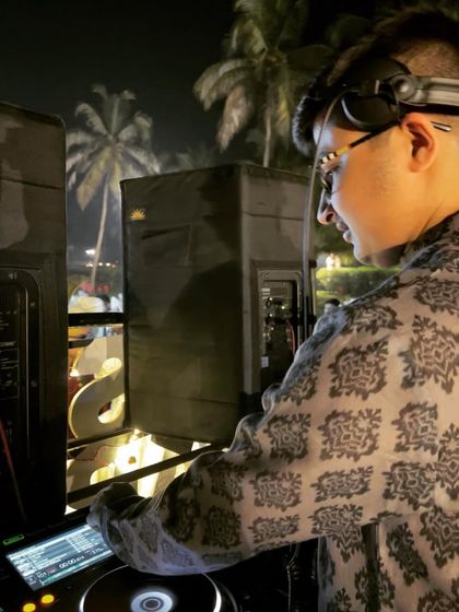 A side profile shot, focused on the mix during a Baraat with a beautiful beachside setting at night.