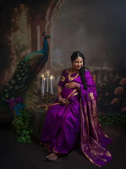 Seated by a candelabra, the expectant mother glows in the soft light. This setup is designed to create a sense of intimacy and timelessness.