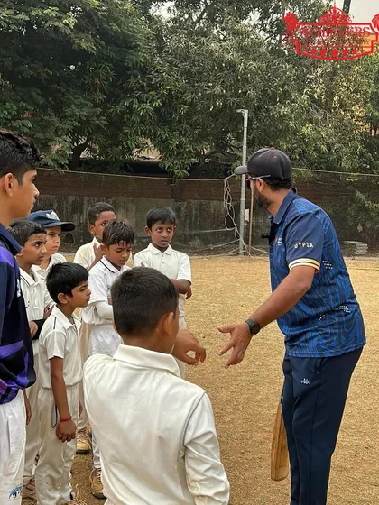A coach having a discussion with a group of young players on the field. We teach game awareness and strategy alongside physical skills.