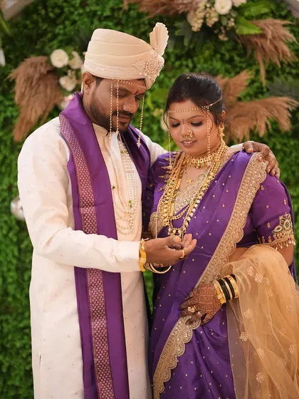 The groom places a ring on the bride's finger during the ceremony. This shot shows a side profile of her traditional hairstyle and makeup.
