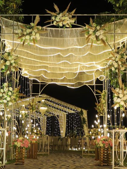 A wide shot of the beautiful Sangeet decor, featuring fairy lights, floral arrangements, and an elegant entrance archway.