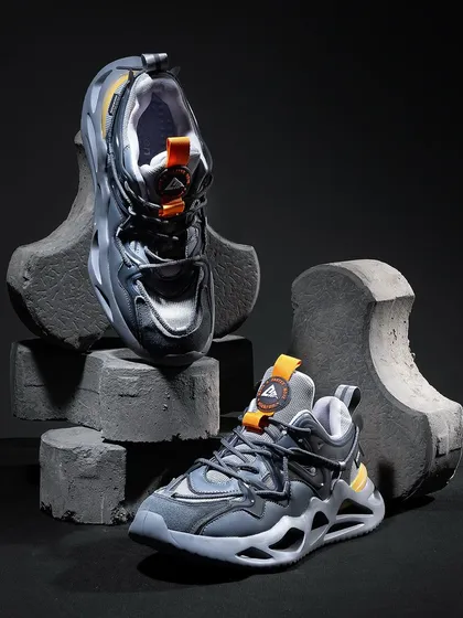 An edgy composition featuring chunky sneakers on concrete blocks. This raw, industrial styling is perfect for a streetwear brand with a tough, urban aesthetic.
