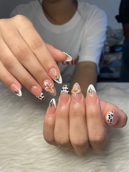 This moody and chic set features a mix of white French tips, cow print accents, and 3D floral charms. A perfect example of combining multiple trends into one cohesive look.