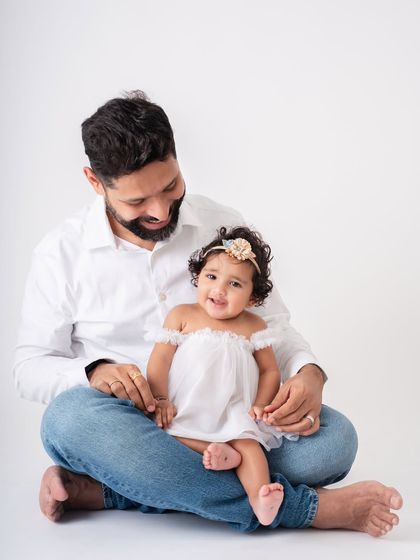 A sweet, quiet moment with dad. The baby is sitting comfortably in her father's lap, a picture of contentment and security.