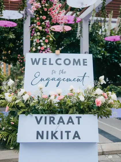 A close-up of the welcome sign for Viraat and Nikita's engagement, surrounded by a bed of fresh white and pink flowers, setting a romantic tone from the very beginning.