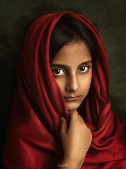 A striking portrait inspired by classic paintings. The young girl's gaze, framed by a rich red cloth, is both powerful and mysterious.