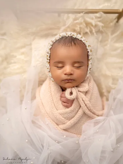 A vision in pink and pearls. This newborn looks so delicate in a soft pink swaddle and a beautiful pearl-adorned bonnet.