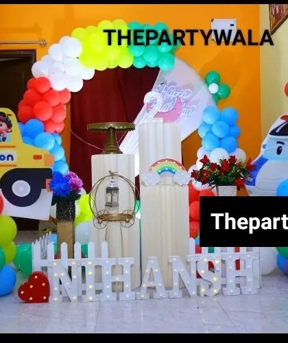 A fun transportation theme featuring a Cocomelon bus and a police car. The colorful balloon arch and light-up name make it a very playful setup.
