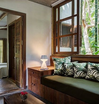 Another view of the Garden Room's lobby, showing a daybed nestled by a large window that frames the tropical foliage outside.