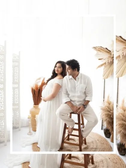 A stylish couple's portrait in a bright, bohemian-themed studio. The clean white outfits and rustic decor create a modern yet timeless feel.