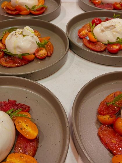 Plates of fresh Tomato and Burrata Carpaccio, ready to be served. The simplicity of the dish highlights the quality of the fresh, seasonal ingredients we use.