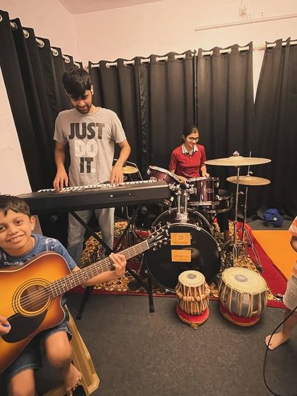 Students gearing up for our monthly jam session. You can see a full band setup with guitar, keyboard, drums, and even a singer.