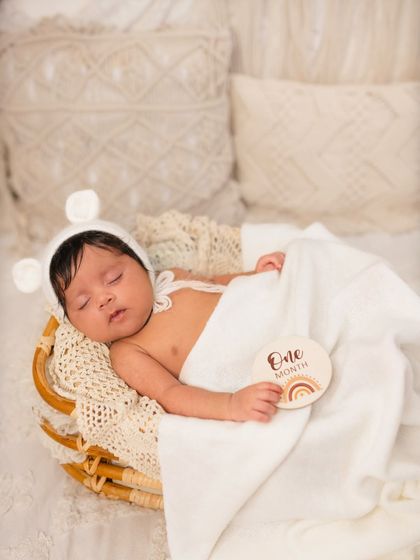 A peaceful one-month-old baby nestled in a basket, wearing an adorable bear bonnet. My milestone sessions focus on simple, beautiful props that keep the focus on your little one.