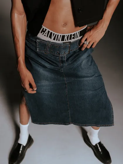A wider view of the denim skirt styling, showing how it pairs with classic loafers and socks. This shot provides a complete look at a more fashion-forward interpretation of the brand.