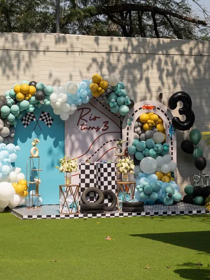 A full view of the race car party backdrop. The combination of balloons, checkered patterns, and tire props creates a dynamic and exciting photo wall.