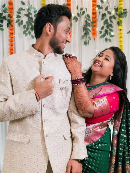 A bride laughing as she leans on her groom's shoulder.