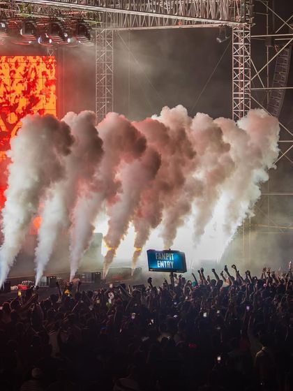 A huge volley of CO2 smoke blasts from the front of the stage, obscuring the crowd in a wave of energy.