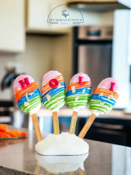 Colourful Holi-themed cakesicles, perfect for sharing the festive joy. Each one is decorated with a rainbow of colours to match the spirit of the festival.