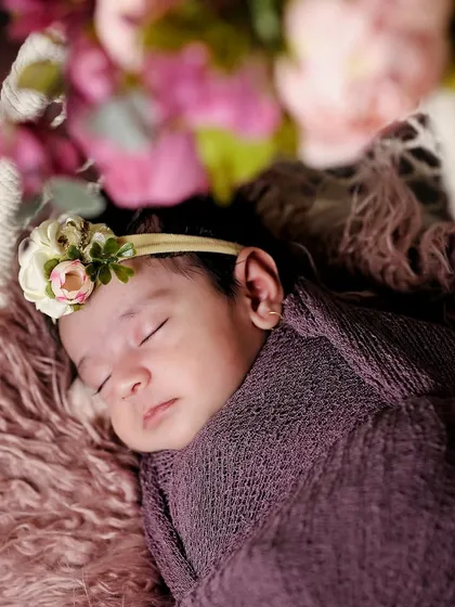 A close-up on a sleeping baby's face, framed by out-of-focus flowers. This artistic shot draws attention to the baby's peaceful expression.