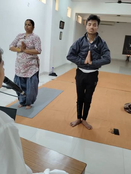 A teacher provides instructions to participants holding the prayer pose in Surya Kriya.