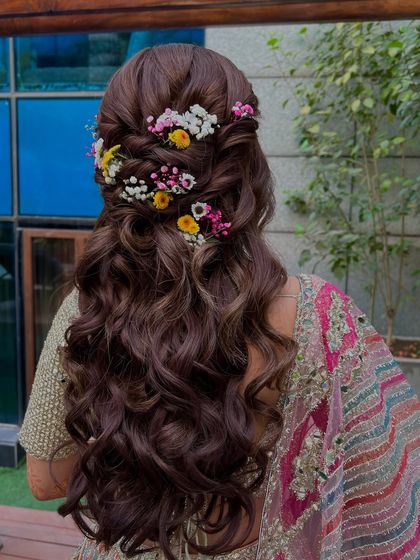 A beautiful half-up style with interwoven twists and a cascade of colorful fresh flowers, perfect for a Mehandi.