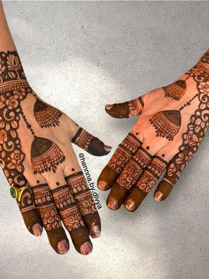 This cutwork bell mehendi is a unique and eye-catching design. The negative space around the jhumkas makes them pop, creating a three-dimensional effect.