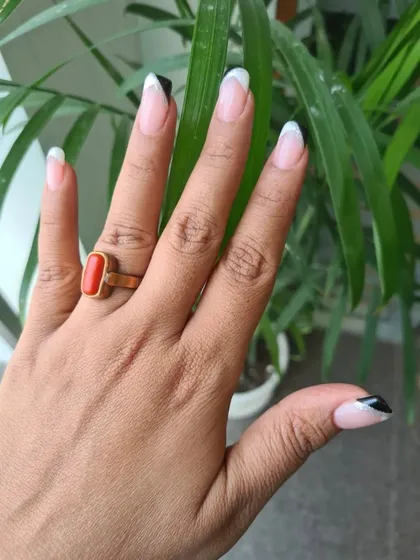 A chic and unconventional French manicure with black and white tips on opposing corners of the nail.