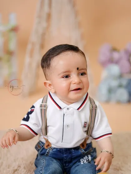 This little gentleman in his polo shirt and suspenders gives a sweet, candid expression during his first birthday session.