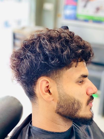 This cut is designed for curly hair, with a gentle taper on the sides to control the shape while letting the curls on top have volume and definition.