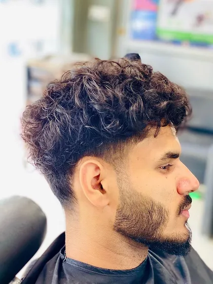 Working with curly hair requires a different technique. I created a taper fade that controls the sides while leaving natural texture and volume on top, complemented by a clean beard line up.
