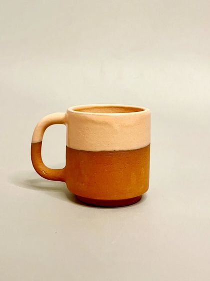 A single two-toned terracotta mug, designed for daily use. Each handmade mug offers a unique blend of functionality and artistry, making every sip a little more special.