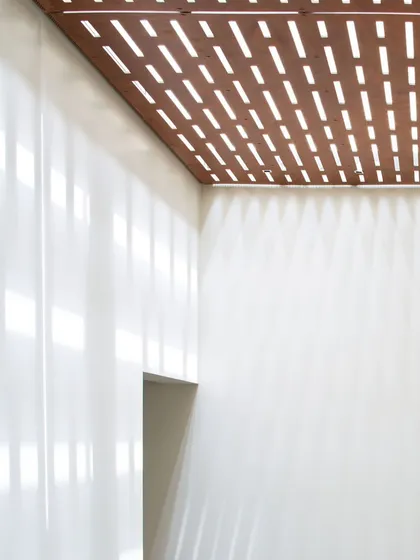Light is a material we sculpt with. For this ceiling, we created a perforated wooden screen that filters light, casting dynamic patterns that shift throughout the day. It’s a detail that transforms the simple act of walking through a corridor into a subtle, poetic experience.