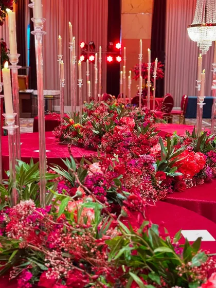 A long shot of the elaborate floral runners that adorned the dining tables. We used a mix of red flowers and fresh greenery, interspersed with tall, clear candle stands to add height and a warm glow to the setting.
