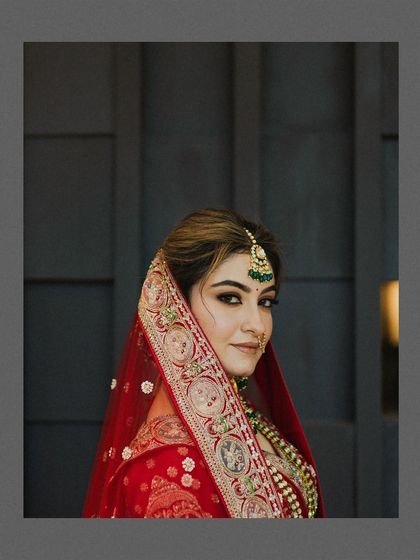 A beautiful portrait of the bride, her red veil framing her face perfectly. The soft, warm light and her direct gaze create a captivating and elegant image.