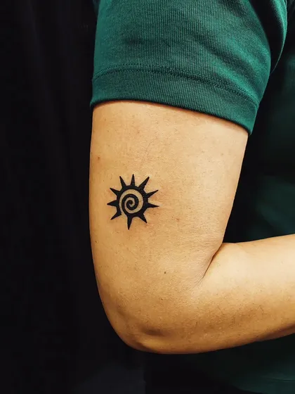 A simple yet striking spiral sun tattoo. This design uses negative space and a bold black spiral to represent energy and life.