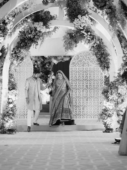 Surrounded by love, she walked towards her forever, hand in hand with her guiding lights. This black and white shot captures the timeless emotion of a father and brother walking the bride down the aisle.