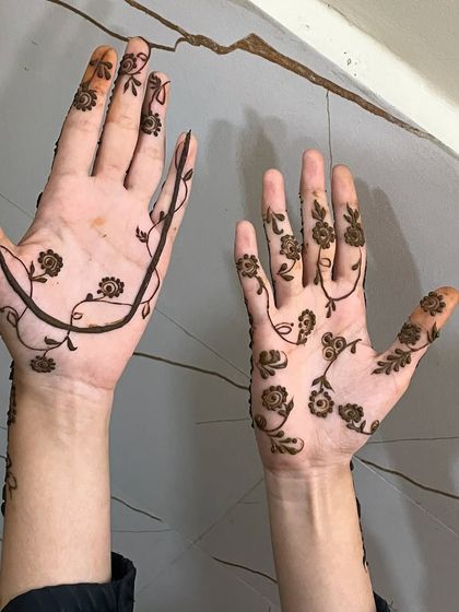 A minimal henna design on one hand and a 'gassa' or vine design on the other.