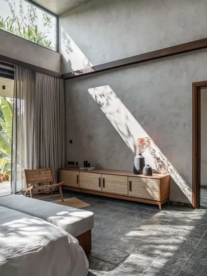 In the 'Antriya' weekend home near Hyderabad, a bedroom opens up to the outdoors, with a shaft of sunlight creating a dramatic pattern across the concrete wall.
